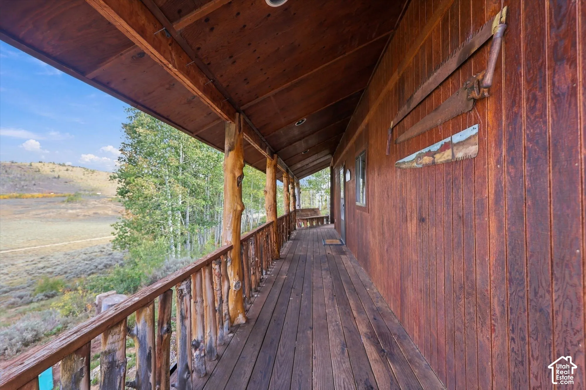 Expansive wood-plank deck with a natural wood railing, supported by rustic log posts