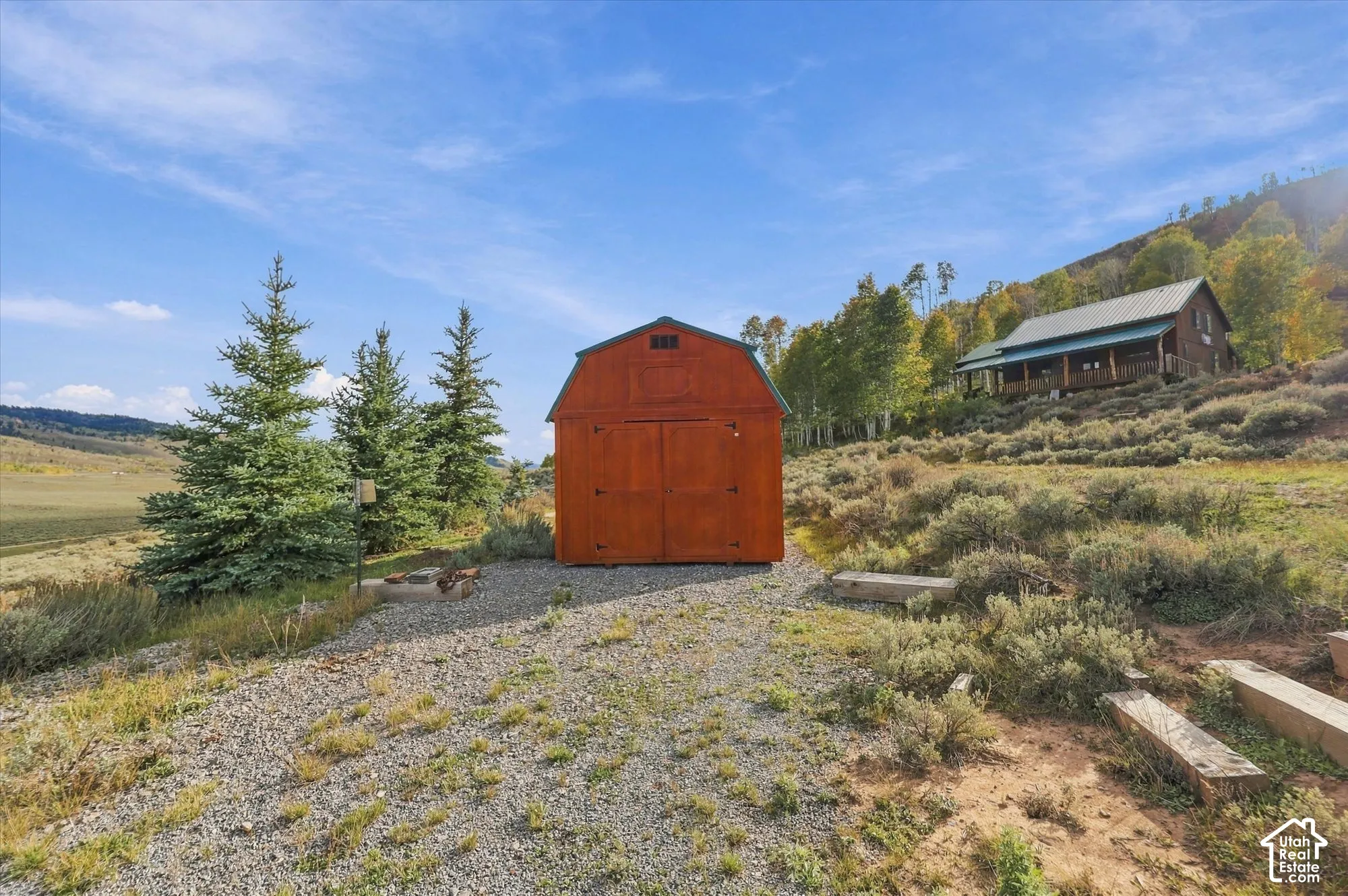 Wood-sided barn structure with double doors, set on a gravel surface