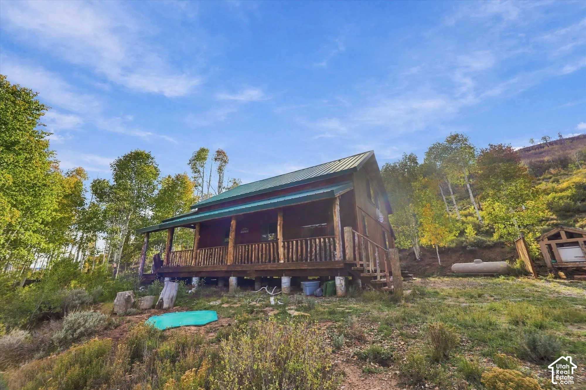 Log cabin exterior with a metal roof and a covered front porch featuring a wood railing
