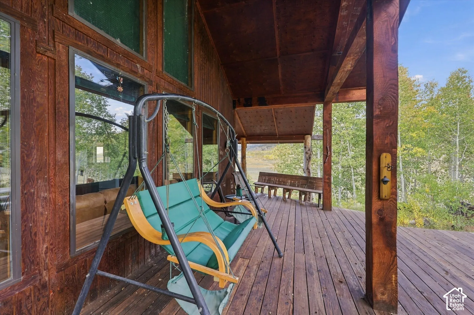 Spacious wooden deck featuring an exposed beam ceiling, wood-finish siding, and multiple windows