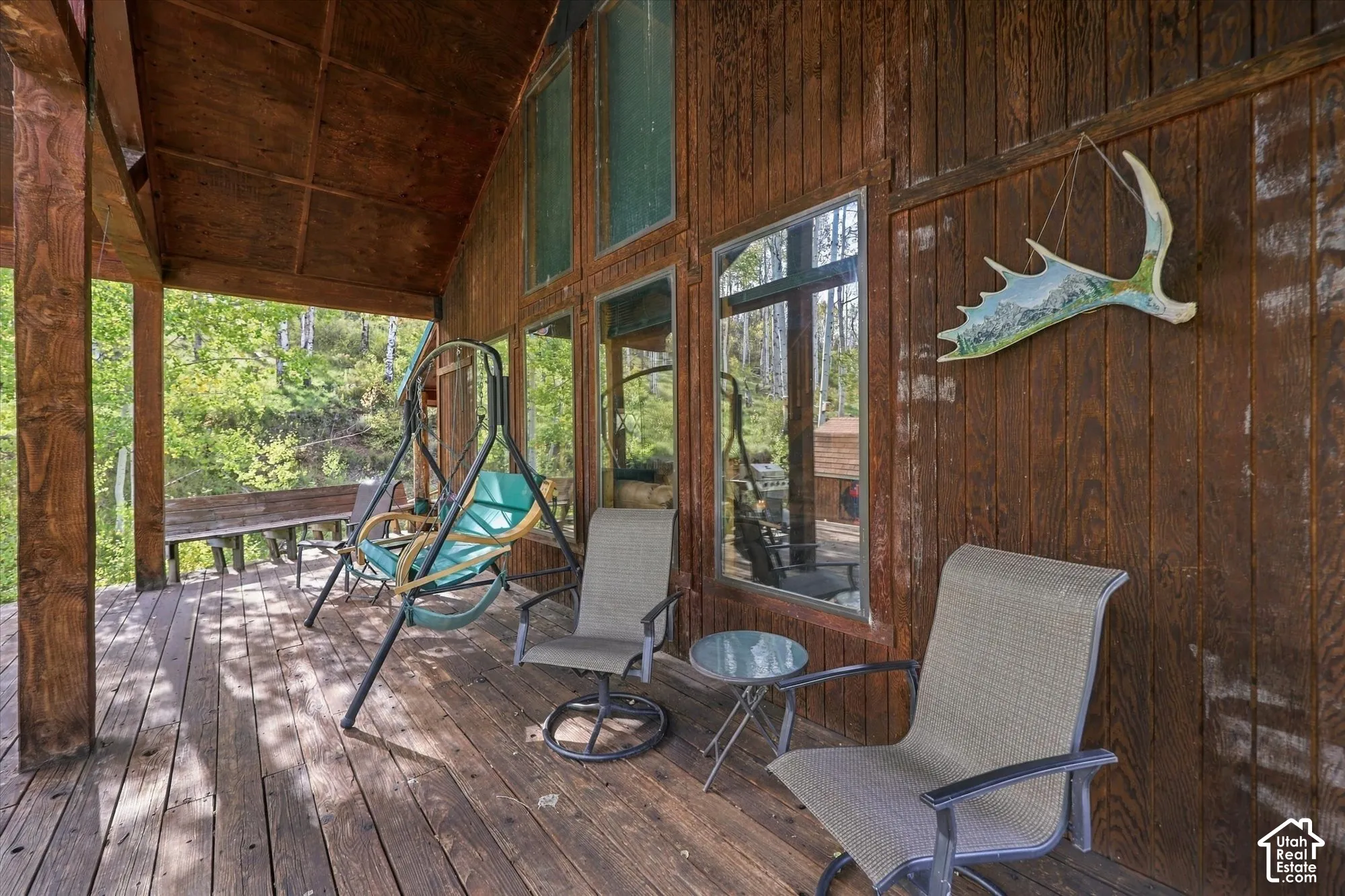 Wood-paneled exterior with floor-to-ceiling windows and a covered wood deck