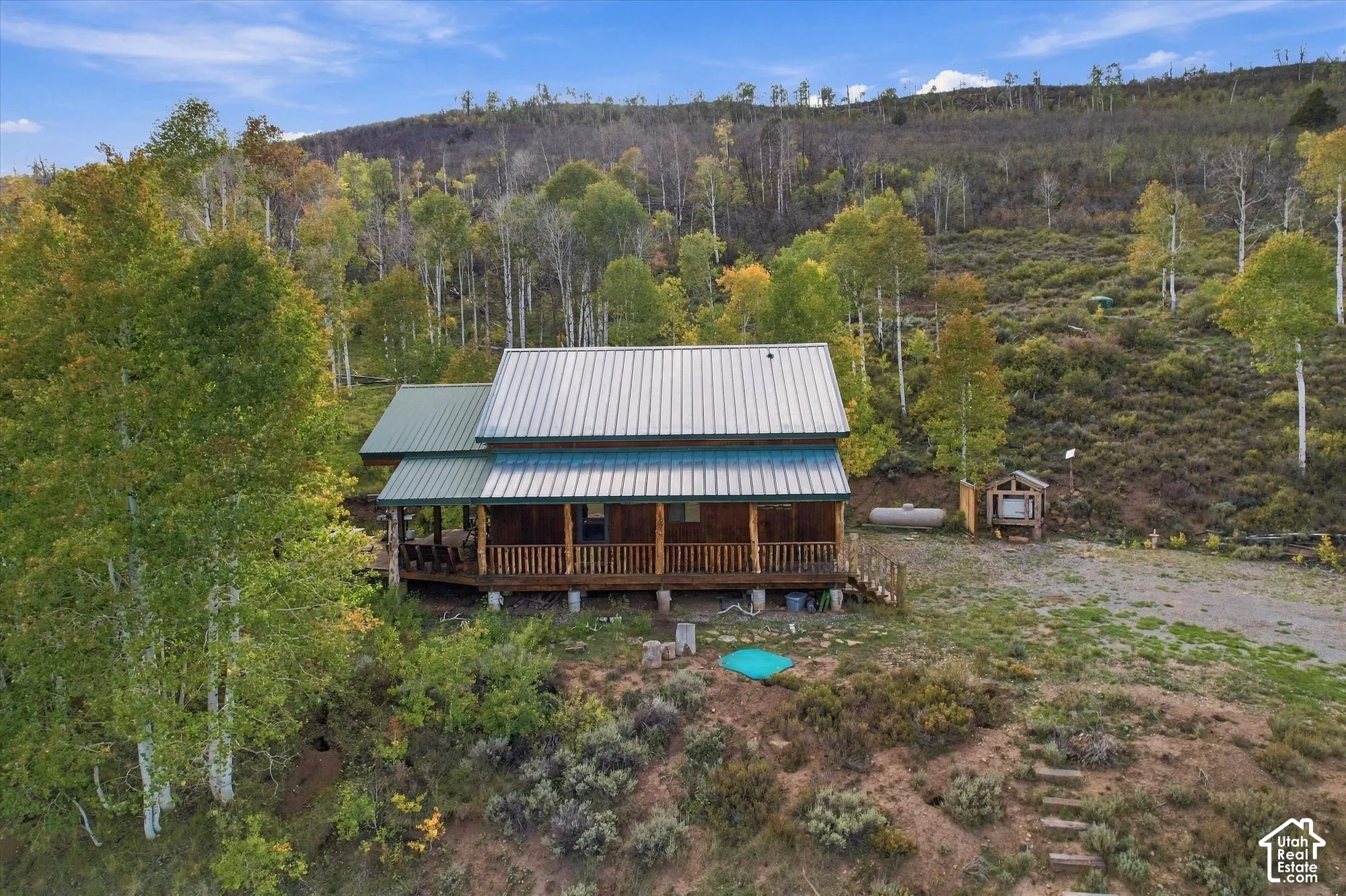 Wood-sided cabin featuring a metal roof and a full-length covered porch with wooden railings