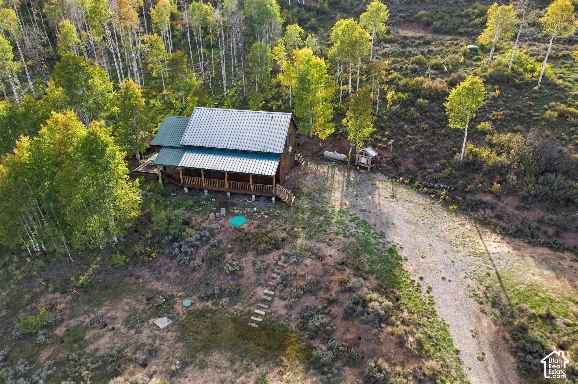 Wood-sided cabin with a green metal roof, featuring an expansive covered porch
