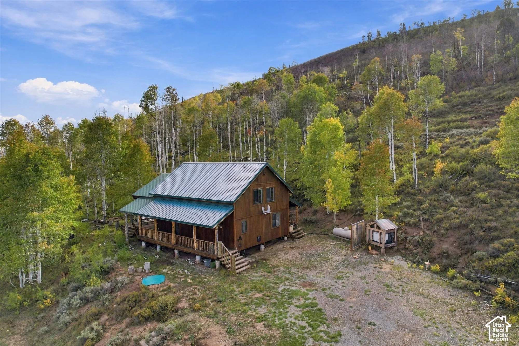 Wood-sided cabin with a metal roof, an extended covered porch, and a raised foundation