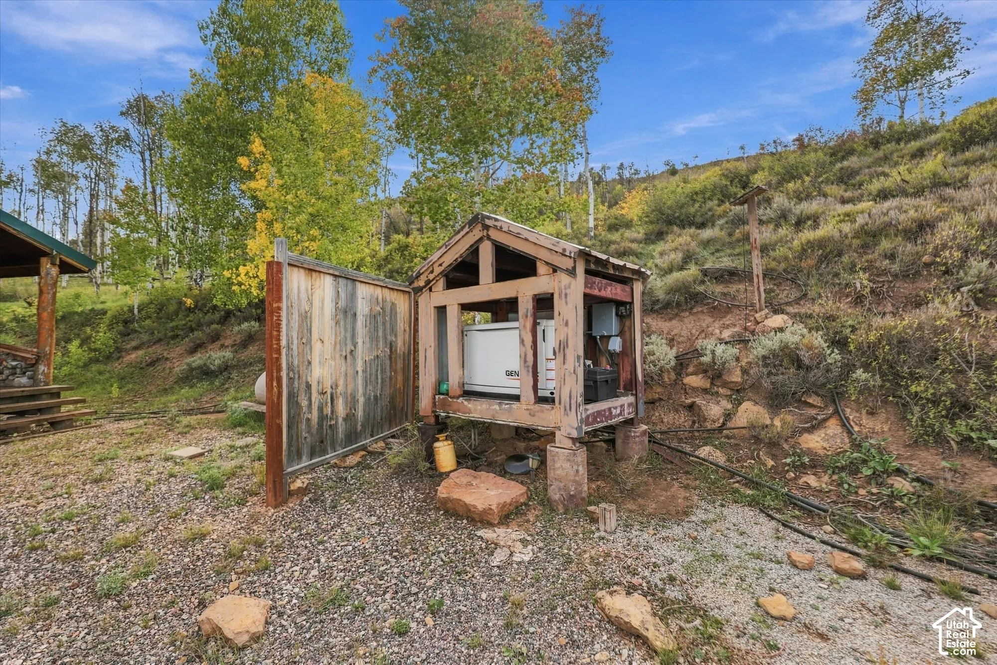 Detached utility shed housing a generator, with natural rock landscaping and mature trees