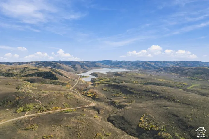 Expansive terrain featuring rolling hills, a prominent body of water, and natural foliage