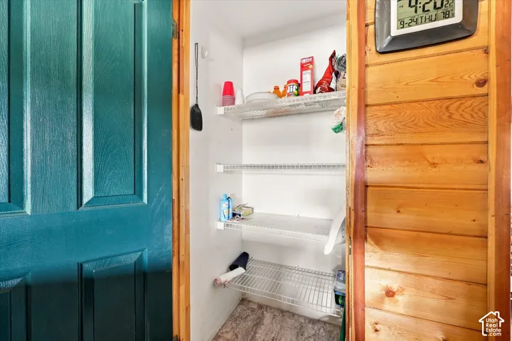 Pantry with multiple wire shelving units, a paneled door, and wood-finish wall paneling