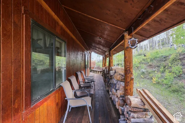 Covered porch with wood-plank flooring, wood-paneled walls, and rough-hewn support posts