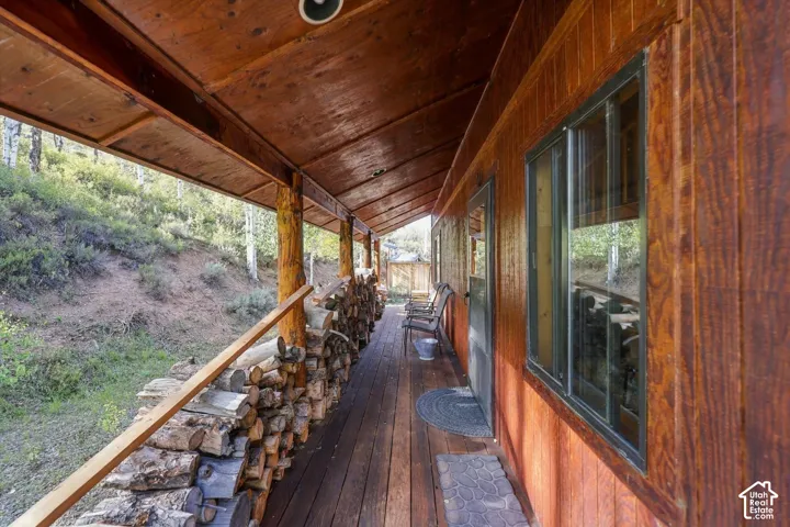 Expansive covered porch featuring a wood-plank floor, exposed wood beam ceiling, and a wood plank exterior