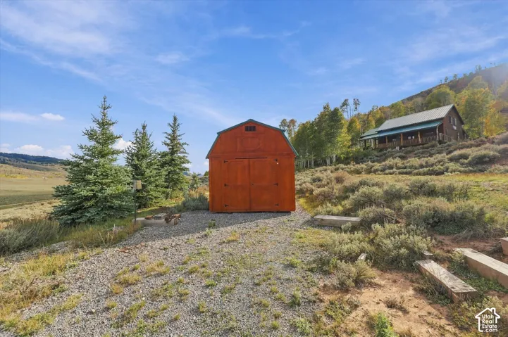 Wood-sided barn structure with double doors, set on a gravel surface