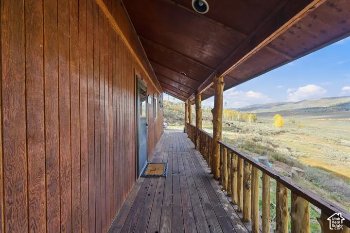 Expansive wood-plank deck with a rustic log railing, recessed lighting, and a wood-paneled exterior