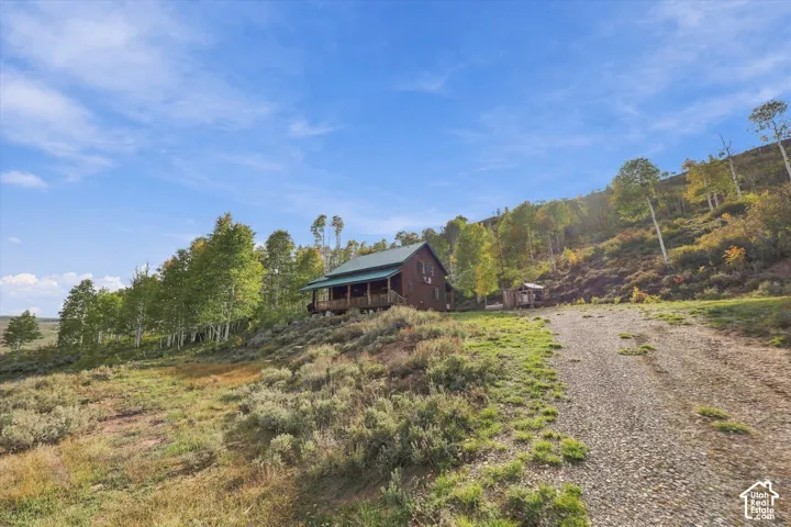 Log cabin exterior with a green metal roof, covered porch, and exposed wood beams
