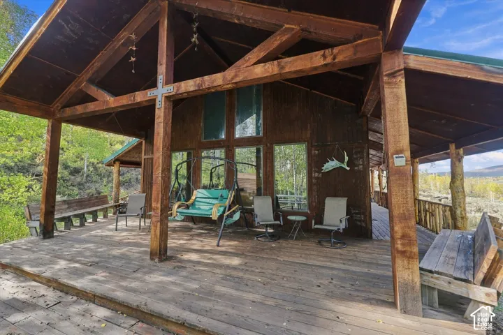 Expansive wood deck with a covered porch, exposed wood beam construction, and large windows