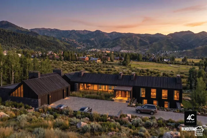Contemporary exterior featuring dark wood siding, multiple large windows, a paver driveway, and mountain scenery