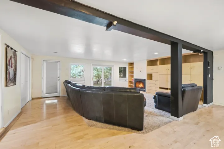 Wood-finish flooring, built-in shelving, fireplace, and multiple windows