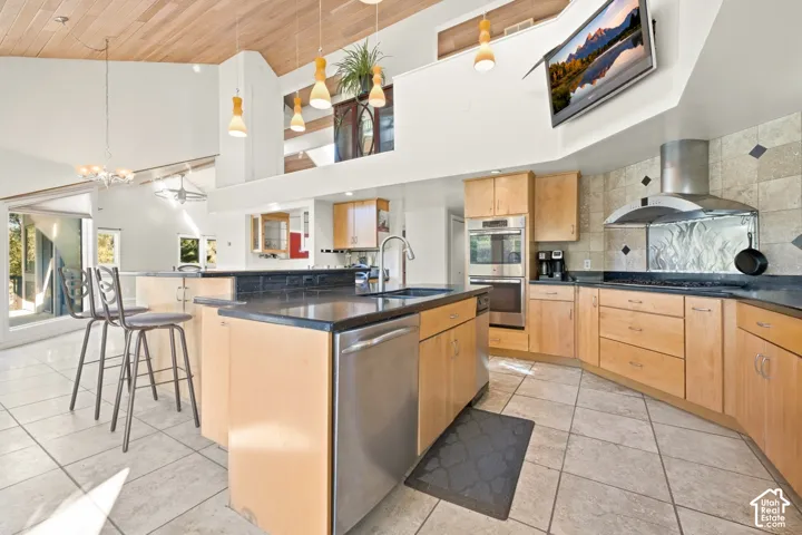 Kitchen featuring wood-finish cabinetry, stainless steel appliances, dark countertops, and tile flooring