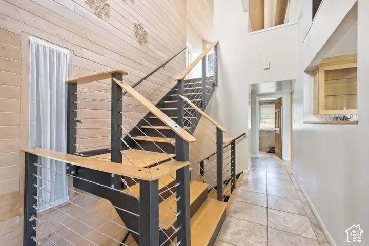 Modern staircase with light wood treads and cable railings, featuring a light wood accent wall