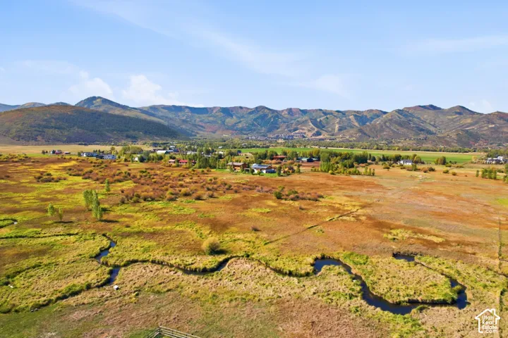 Expansive open land with natural waterways, distant mountain backdrop, and scattered residential properties