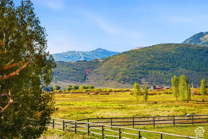 Expansive open field bordered by a wooden fence, with distant mountain ranges