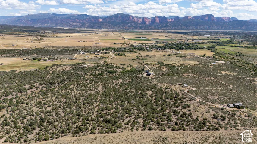 Expansive undeveloped acreage with varied terrain, featuring several structures and a natural landscape