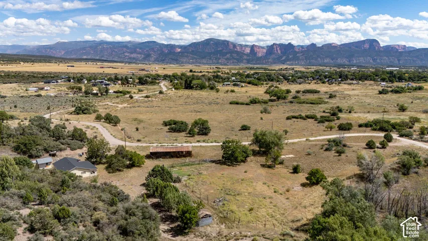Expansive land with natural vegetation, a residential structure with a dark roof, and an additional smaller structure