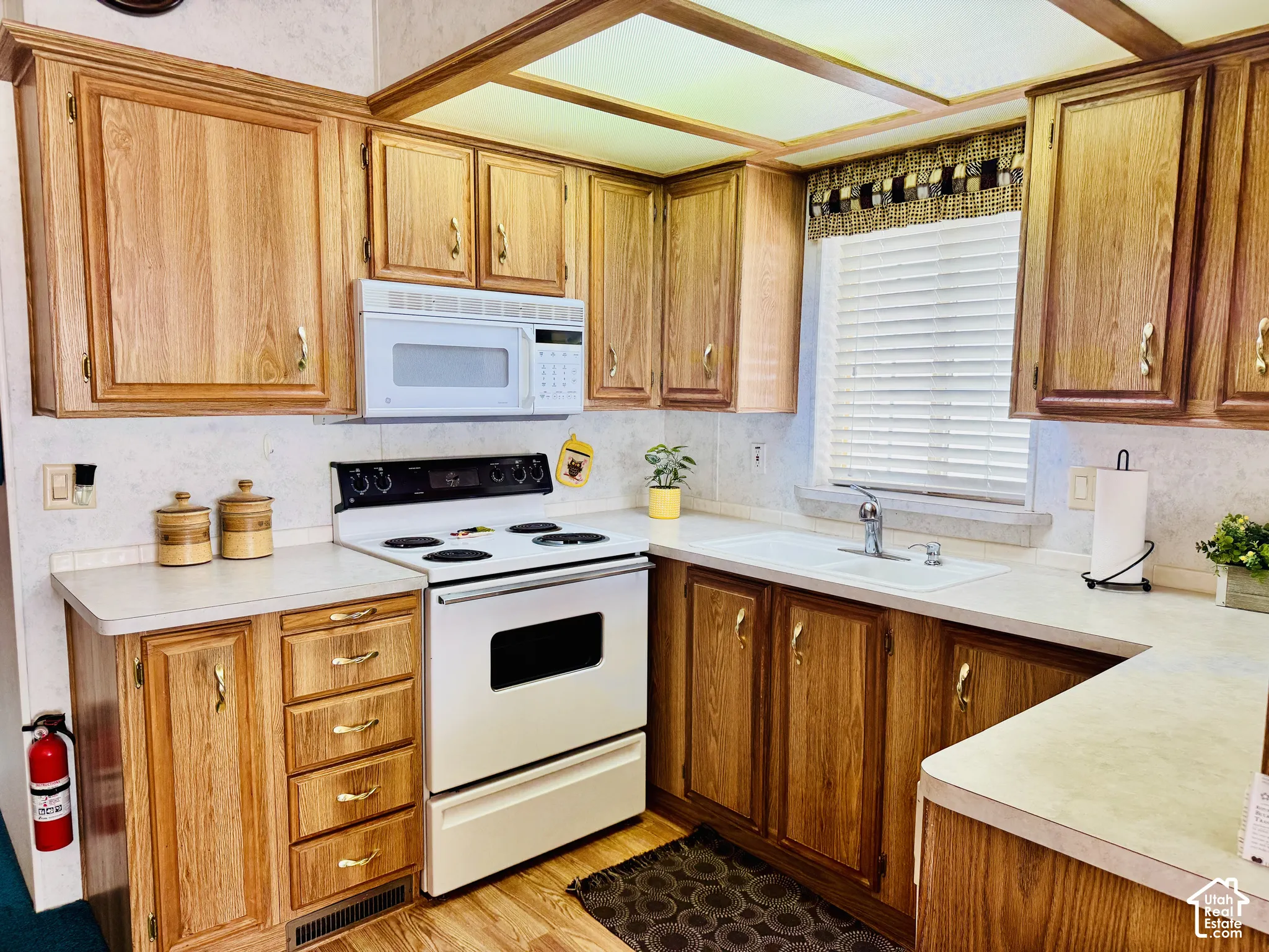 Kitchen featuring wood-finish cabinetry, white countertops, built-in microwave, and electric range