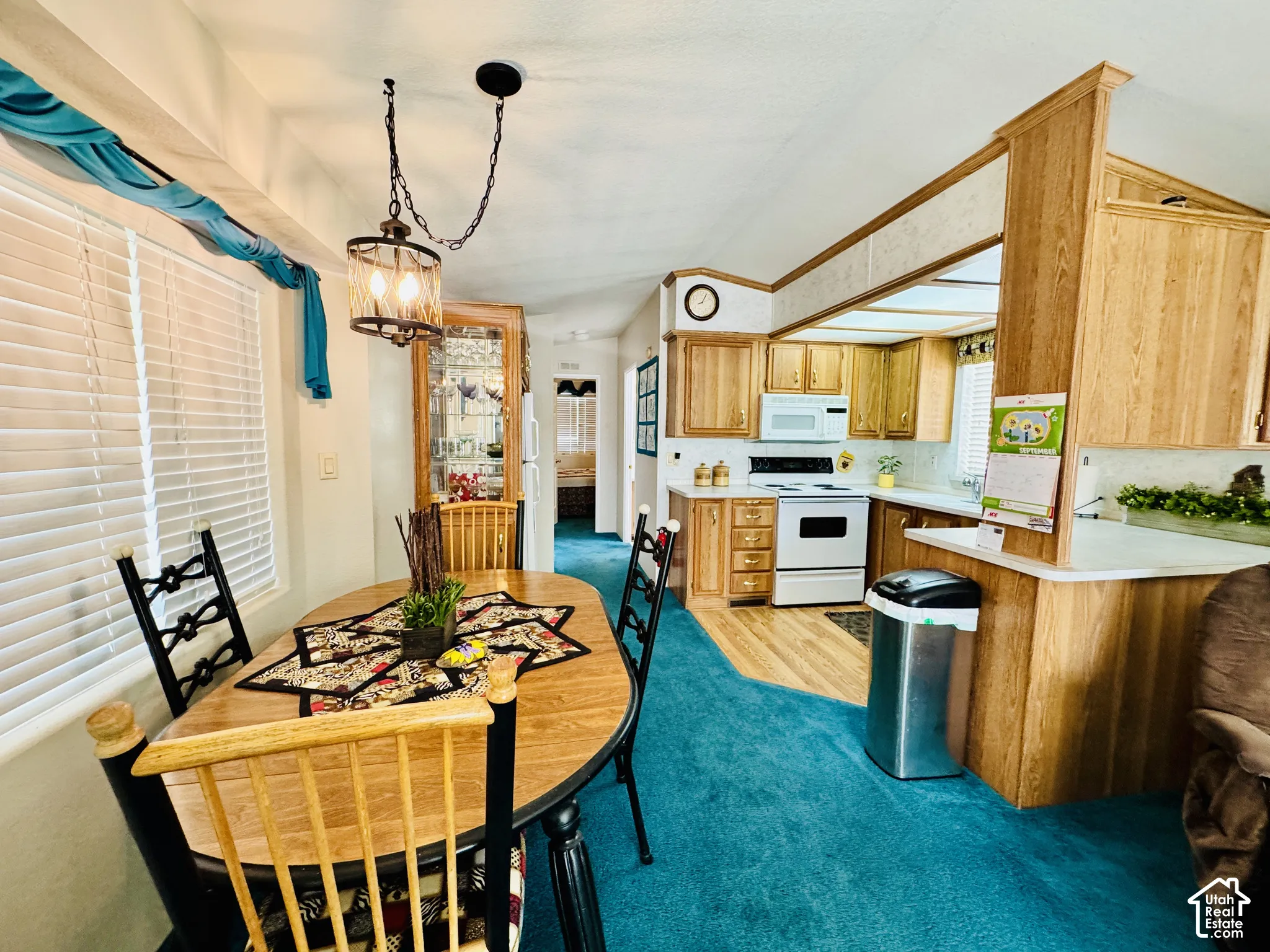 Kitchen and dining area featuring wood-finish cabinetry, white appliances, and a built-in breakfast bar