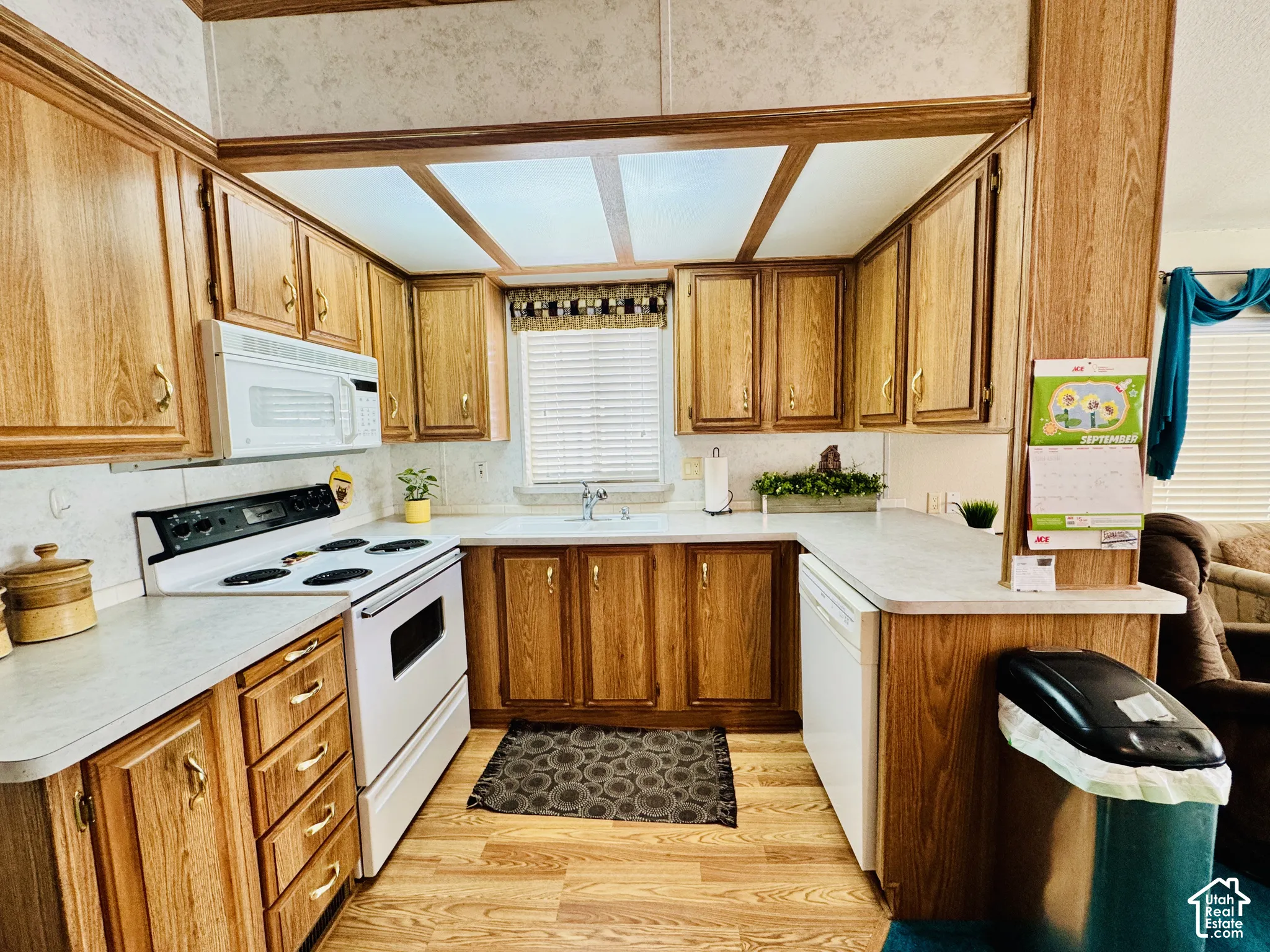 Kitchen featuring wood-finish cabinetry, white countertops, built-in microwave, and a white electric range