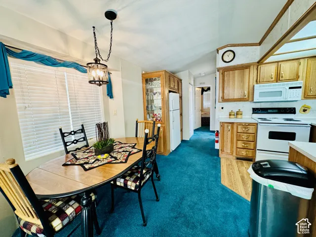 Laminate wood-finish flooring, wood cabinetry with gold hardware, and white appliances