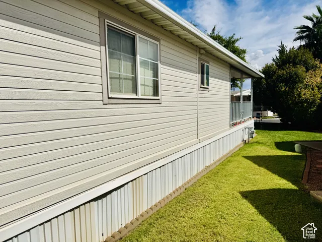 Horizontal siding exterior with a window featuring grid detailing, a covered porch with metal railings, and a grass lawn