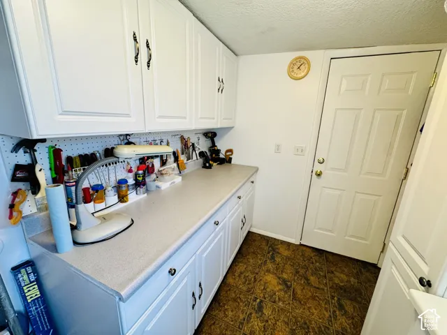 White shaker-style cabinetry with dark hardware, light-toned countertop, and patterned floor tiling
