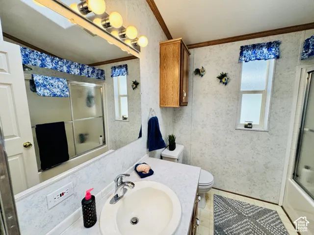 Bathroom featuring a built-in vanity with an integrated sink, wall-mounted light fixture, shower with sliding glass doors, and a window
