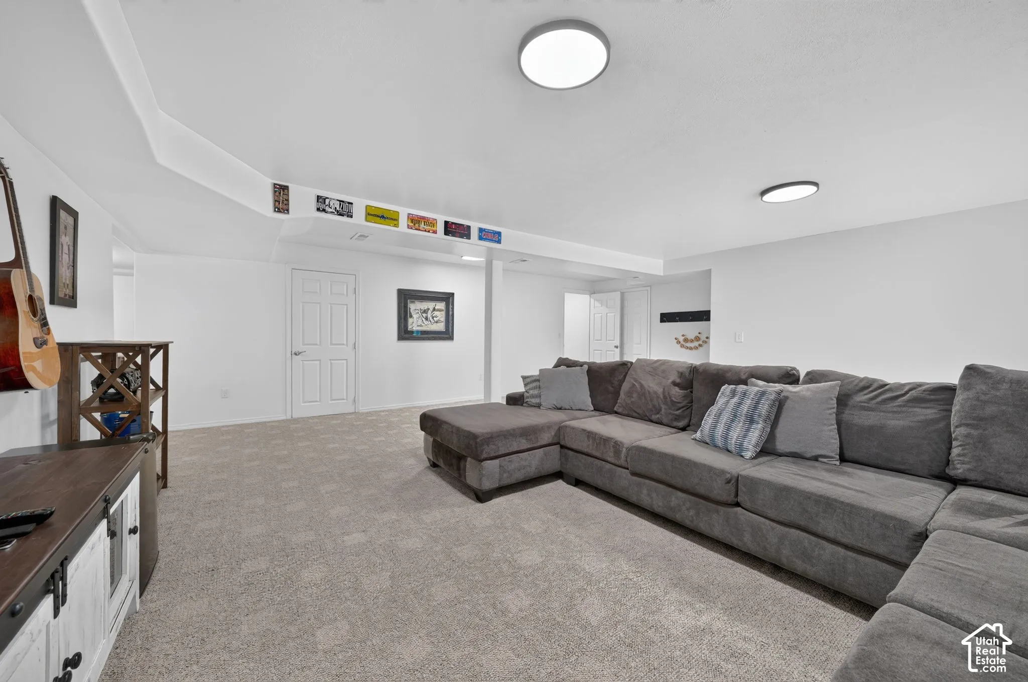 Open-concept room featuring light-toned carpet flooring, recessed ceiling, and multiple flush-mount ceiling light fixtures