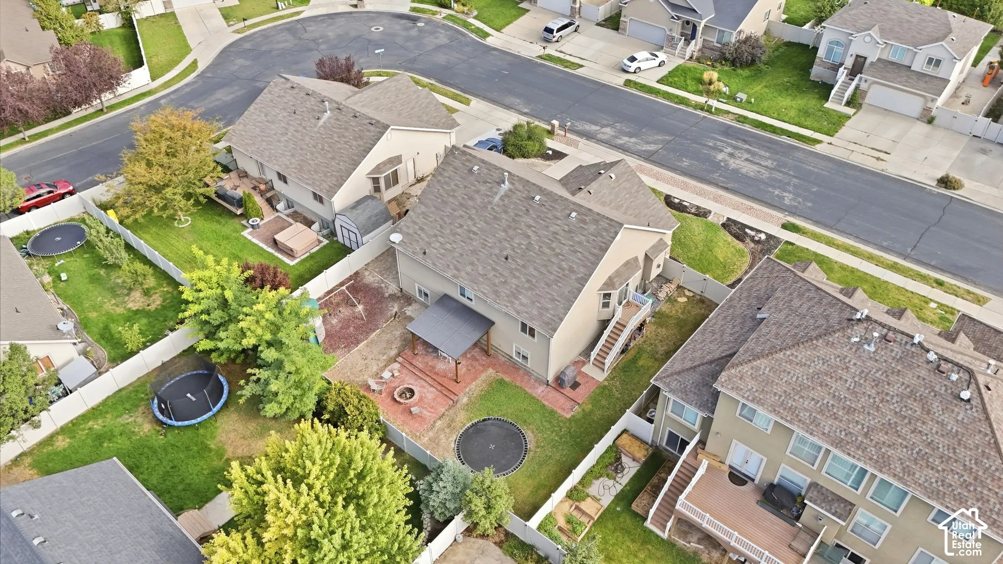 Two-story residence featuring a shingled roof, a covered patio, and a fenced backyard with mature trees