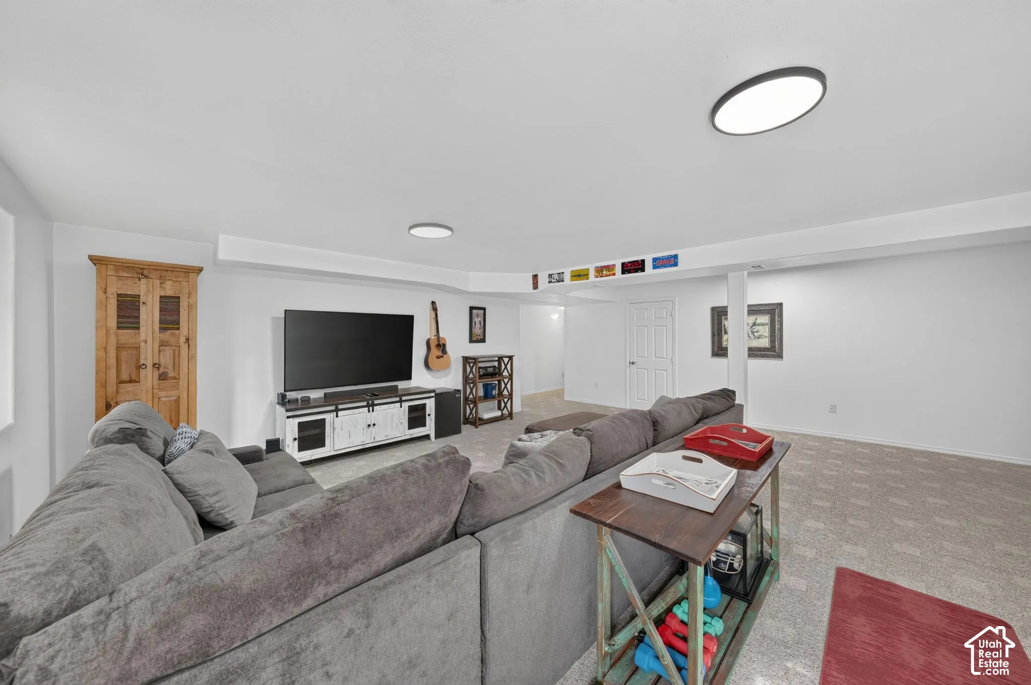 Recessed lighting illuminates this carpeted room, featuring white walls and a white paneled door