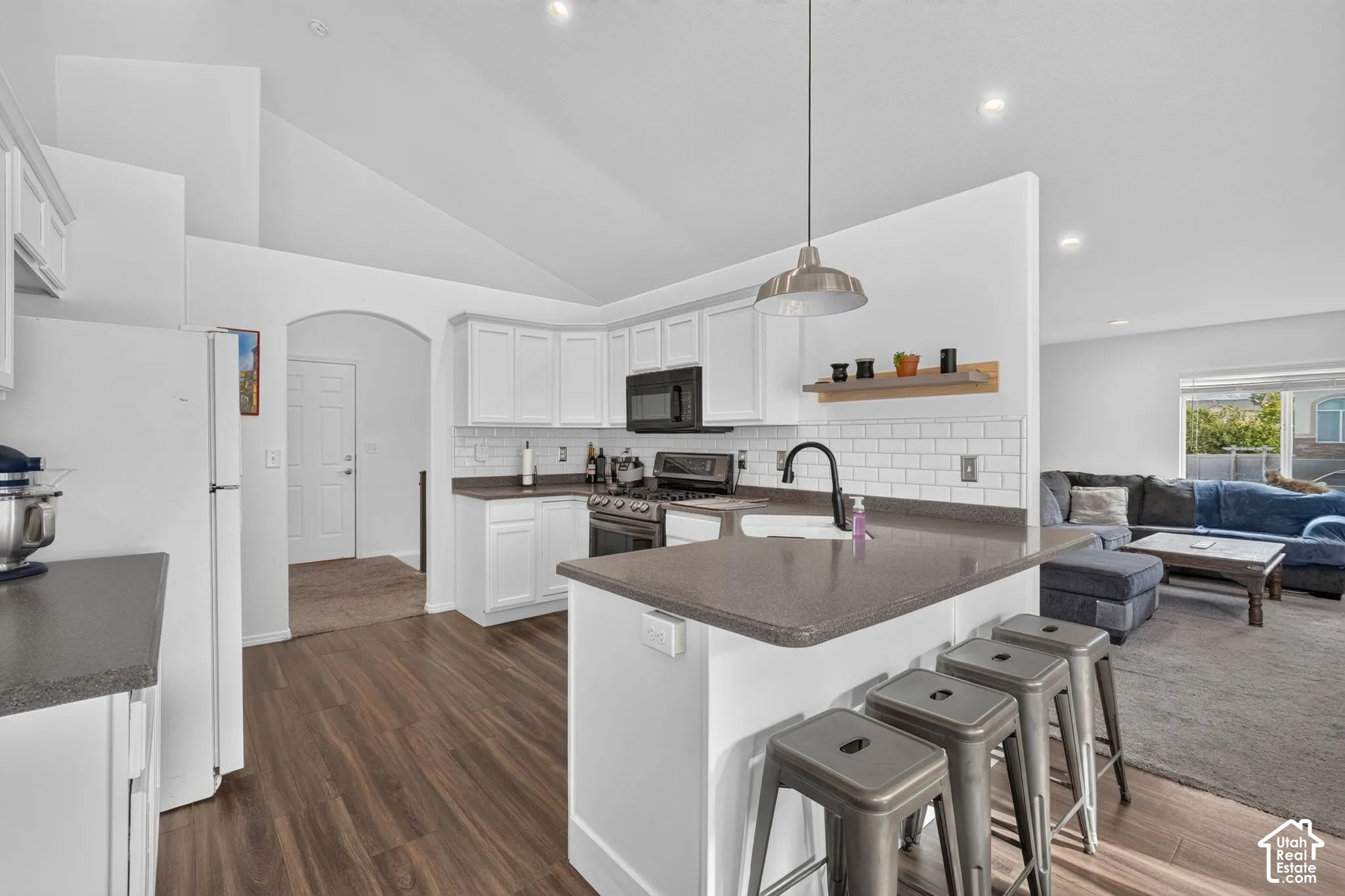 Modern kitchen featuring white cabinetry, stainless steel appliances, and a spacious island with quartz countertop and seating for three