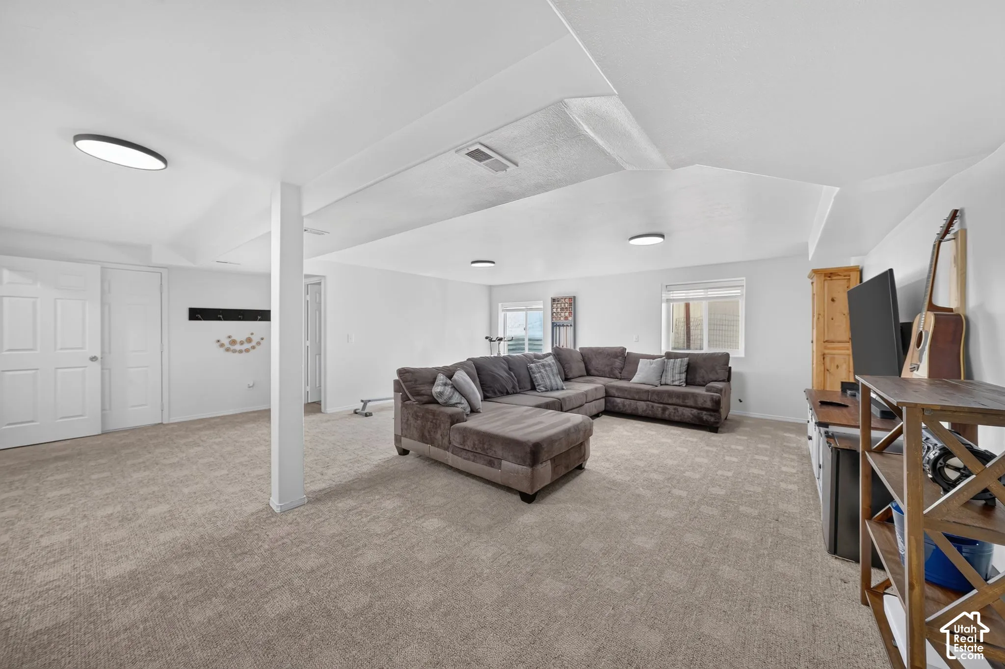 Spacious room featuring neutral carpeting, recessed lighting, white walls, and multiple windows