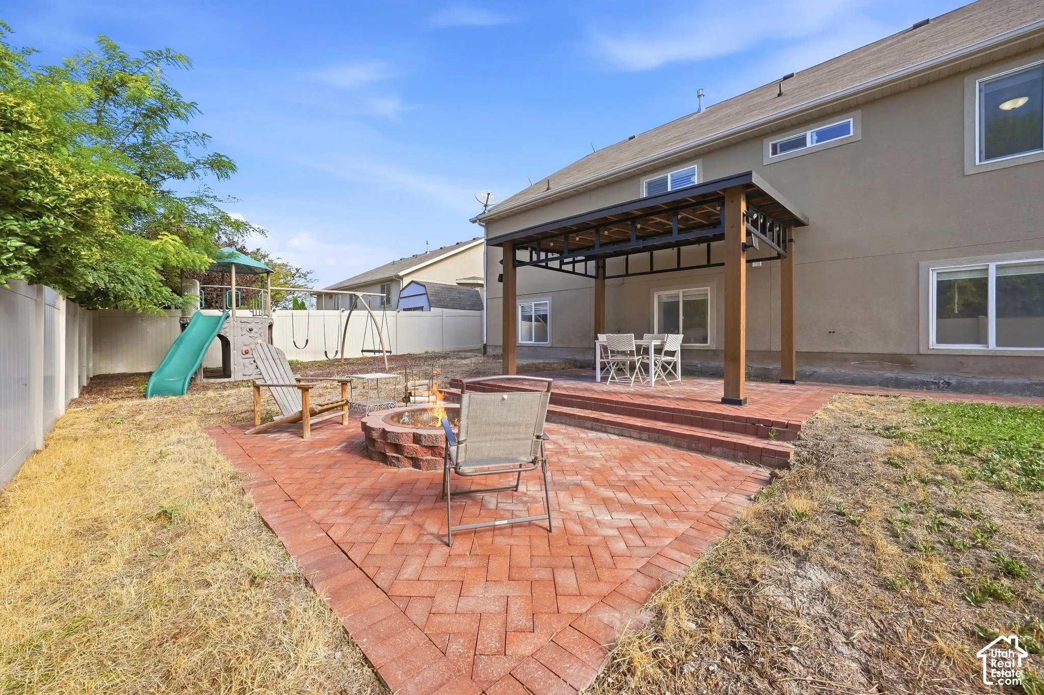Brick paver patio featuring a built-in fire pit and a covered pergola