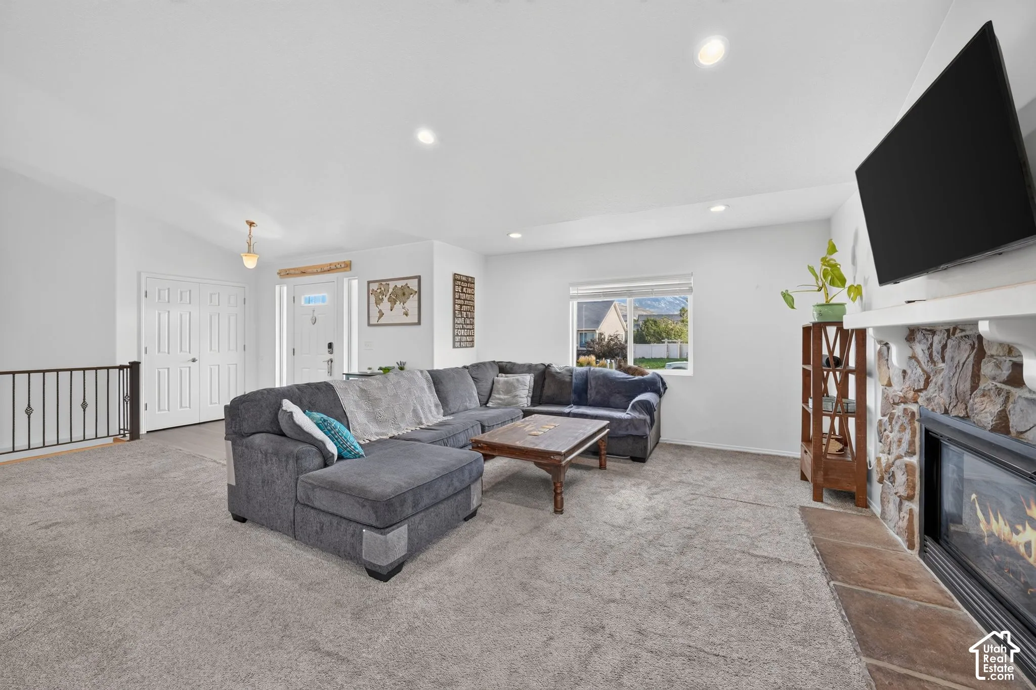 Recessed lighting, vaulted ceiling, stone-clad fireplace with mantel, window, and durable carpeting