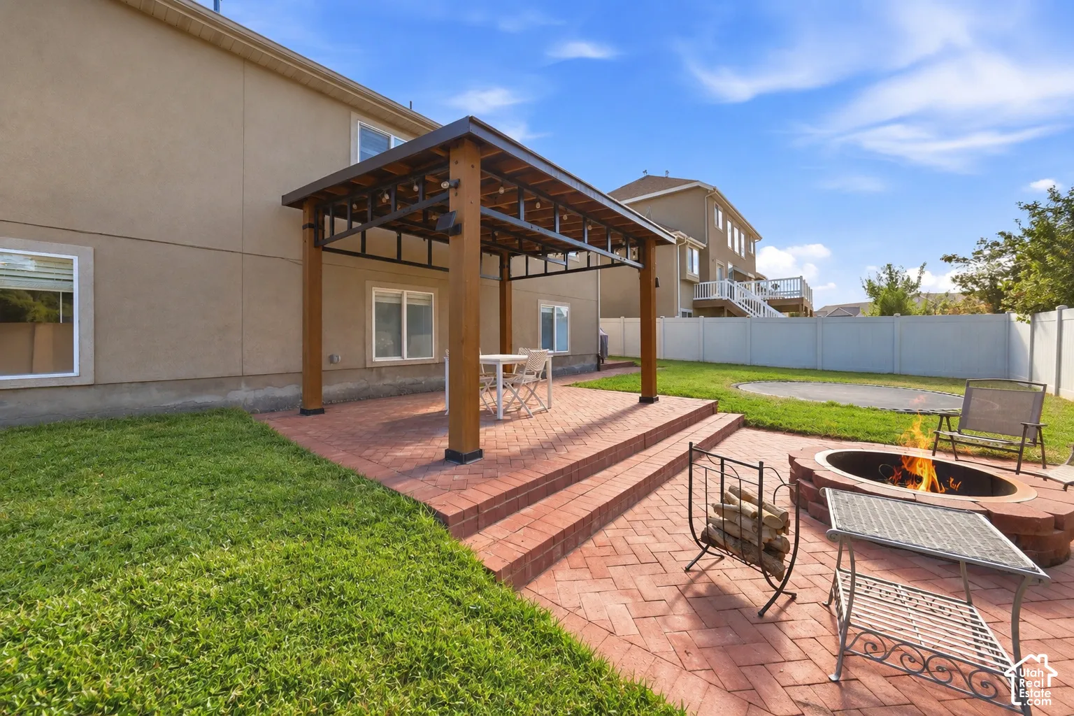 Covered patio with a brick paver surface, integrated steps, and a built-in fire pit