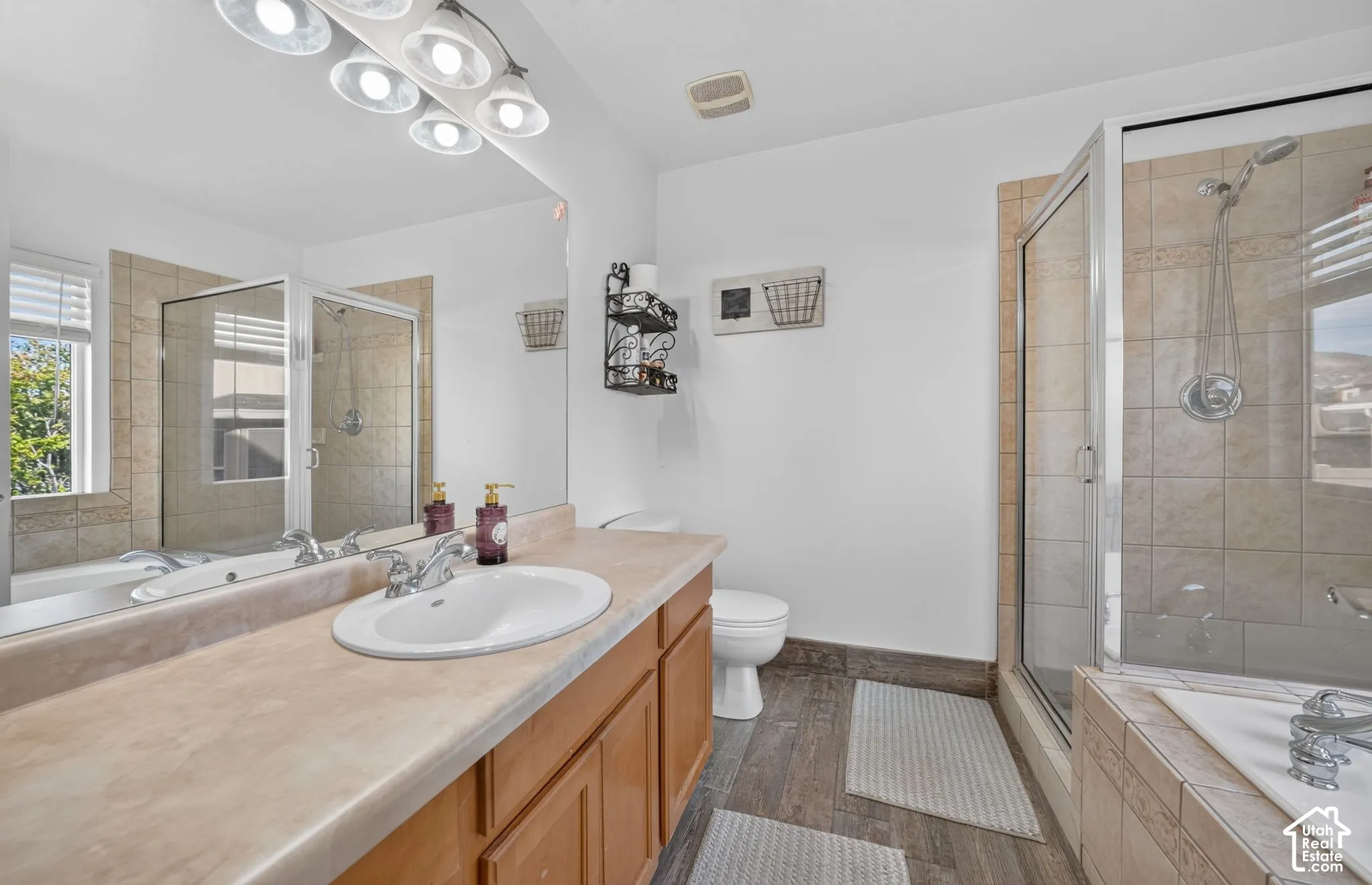 Warm wood-finish vanity with an integrated sink, large vanity mirror, and multi-bulb fixture