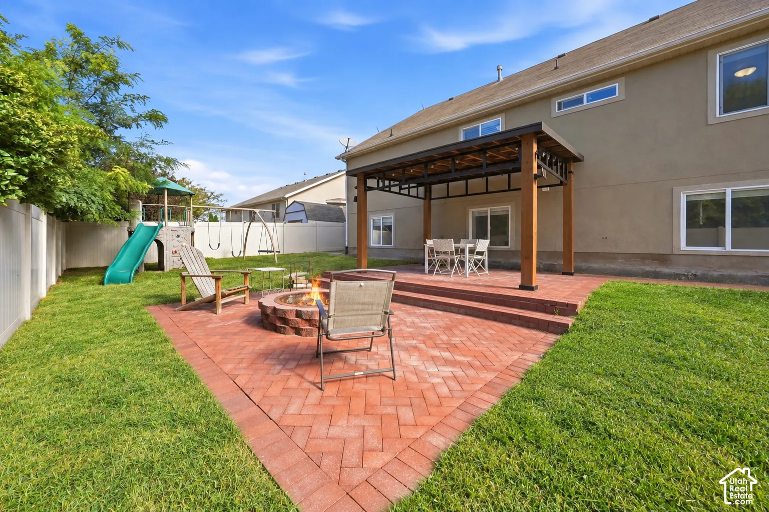 Expansive backyard featuring a brick paver patio, built-in fire pit, covered pergola, and a private perimeter fence