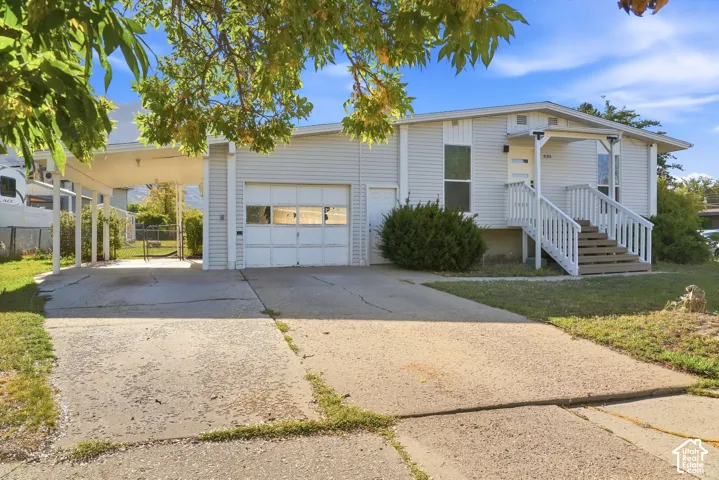 Front exterior featuring a covered entry porch, white siding, attached garage, and an extended carport