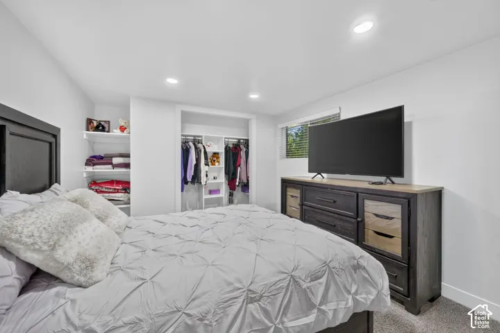 Recessed ceiling lighting, open closet with built-in shelving, white walls, and carpeted flooring