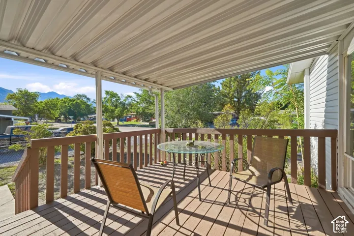 Covered outdoor deck with wood-finish flooring, wood railings, and a corrugated metal ceiling