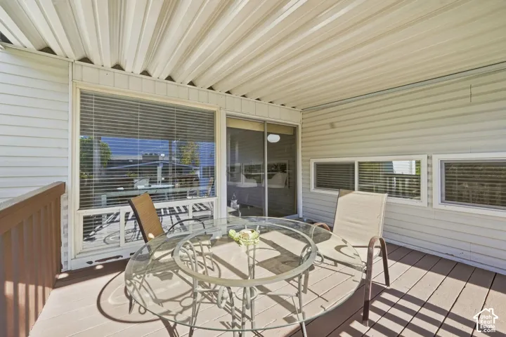Covered patio with composite decking, featuring a large picture window, sliding glass door, and two horizontal windows