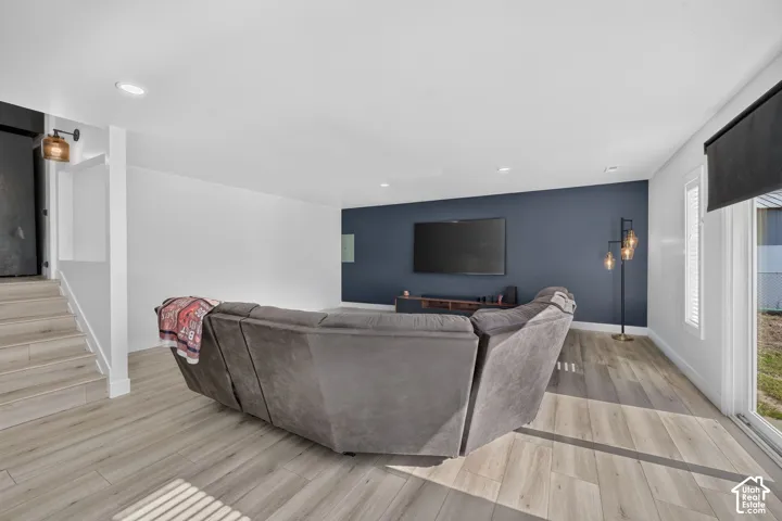 Wood-finish flooring, recessed lighting, accent wall, built-in media console, sliding glass door