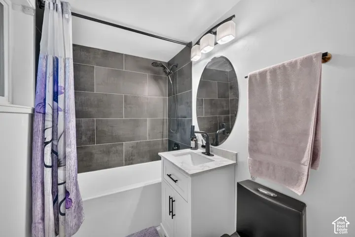 Rectangular subway tile shower surround, white vanity with integrated sink, oval mirror, and black plumbing fixtures