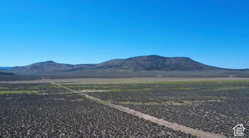 Expansive undeveloped land featuring a dirt road and distant mountains