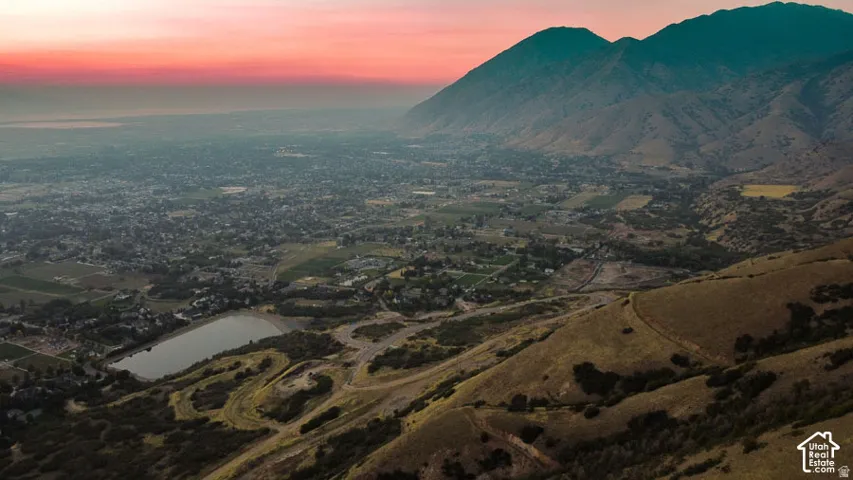 Expansive mountain landscape featuring a large body of water, distant residential areas, and a prominent mountain range